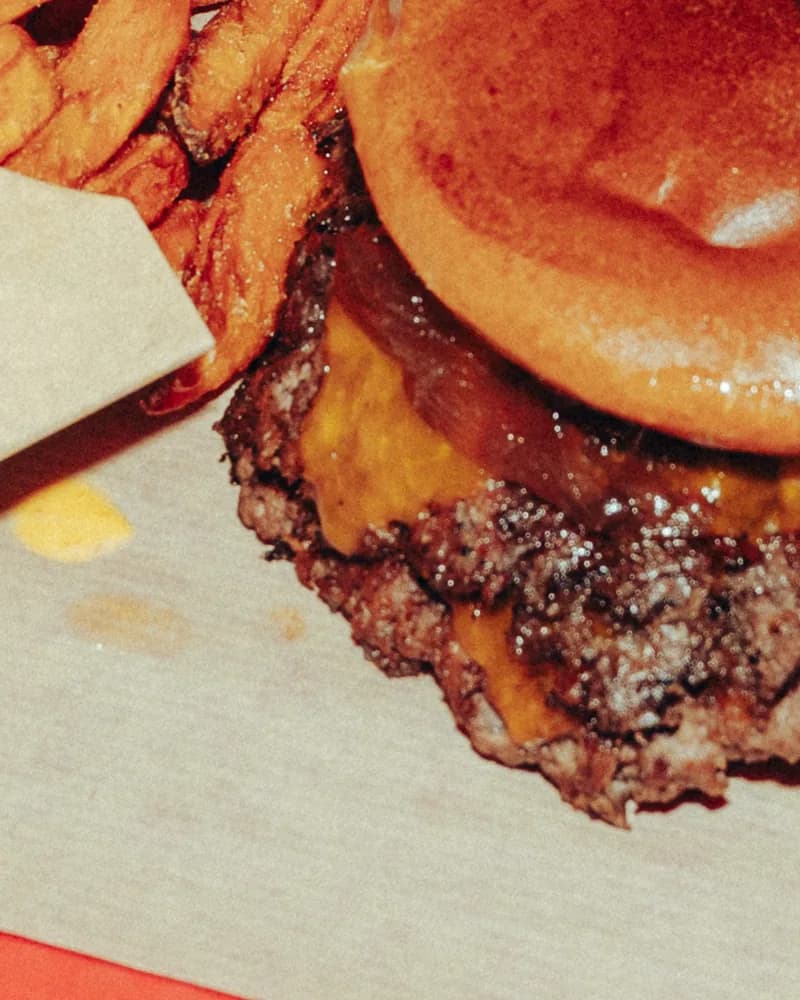 Nahaufnahme des Burgers: geschmolzener Käse und karamellisierte Tropea-Zwiebeln unter dem Brötchen